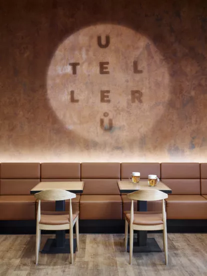 pohled na hnědou stěnu se stoly a logem restaurace